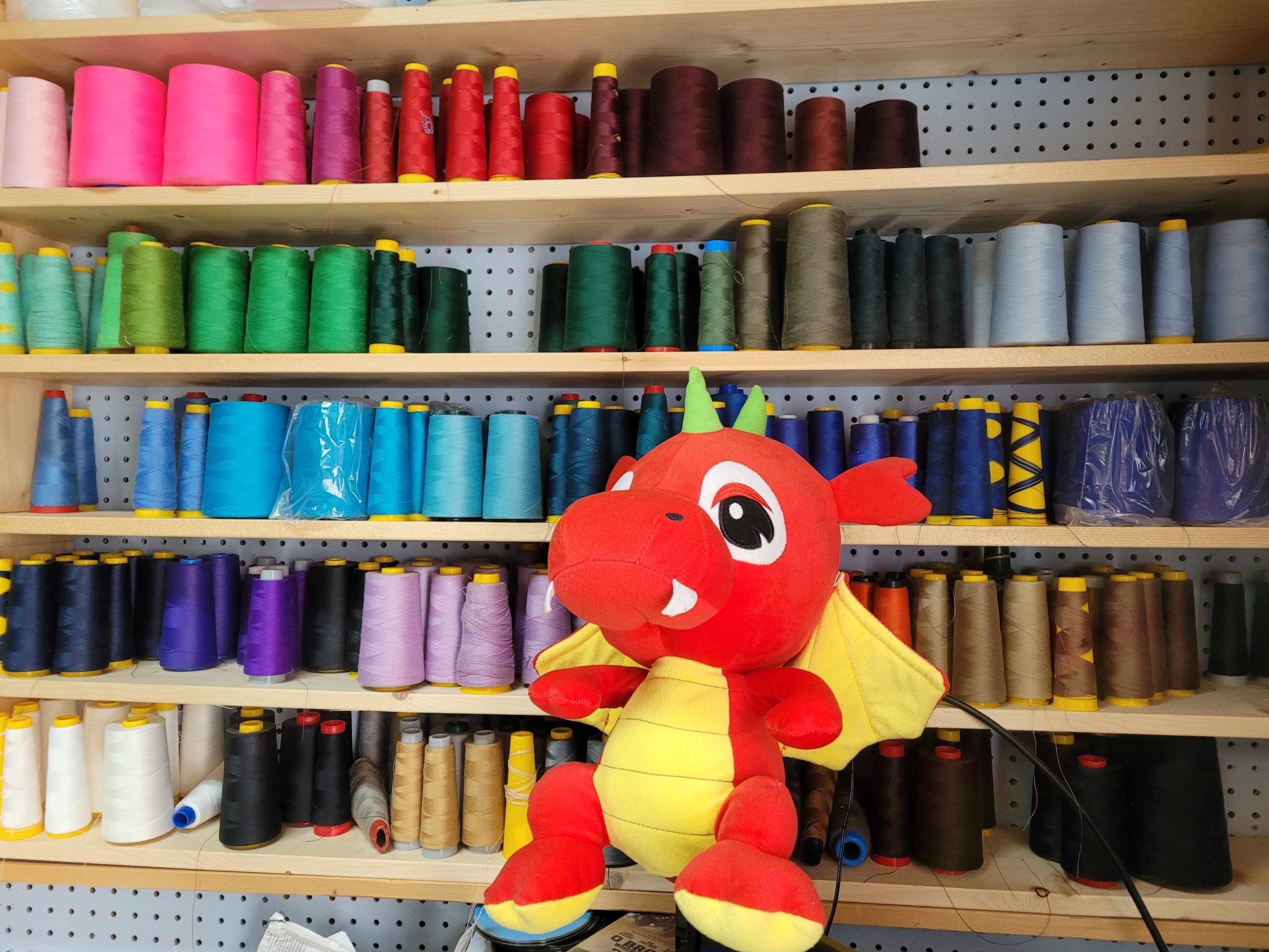 Shelves Of Colorful Thread With A Red Dragon Plushie